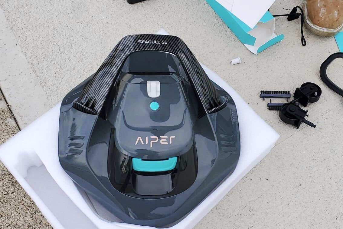 Aiper Seagull SE Cordless Robotic Pool Cleaner with packaging and accessories on cement