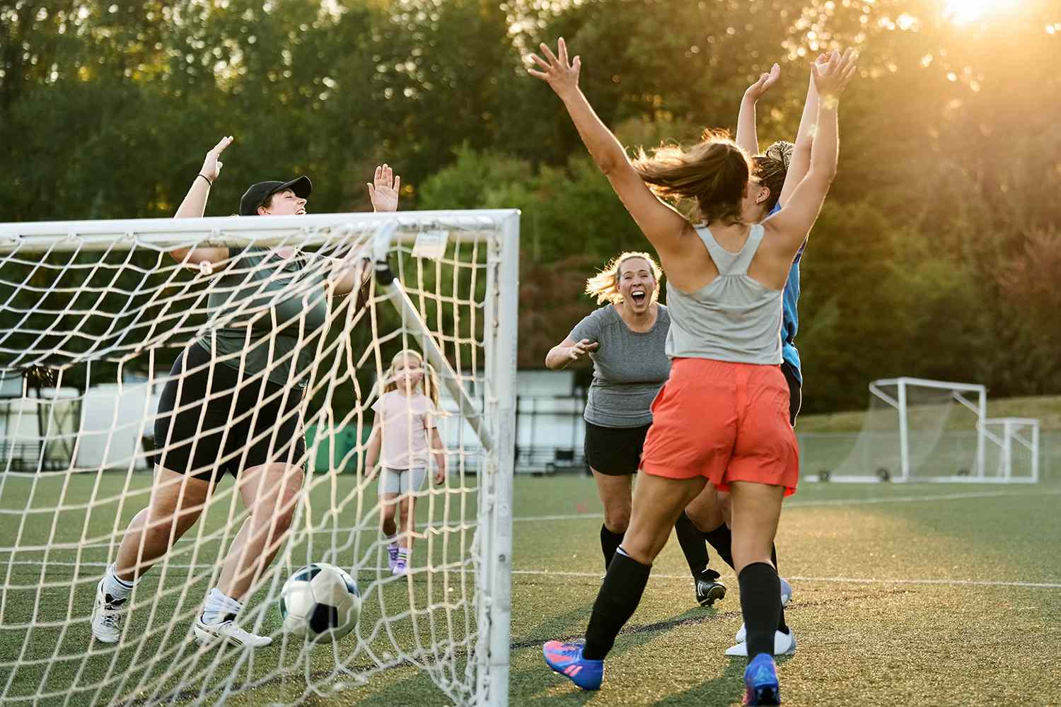 Group of women players cheering and celebrating a goal during team practice session on outdoors field