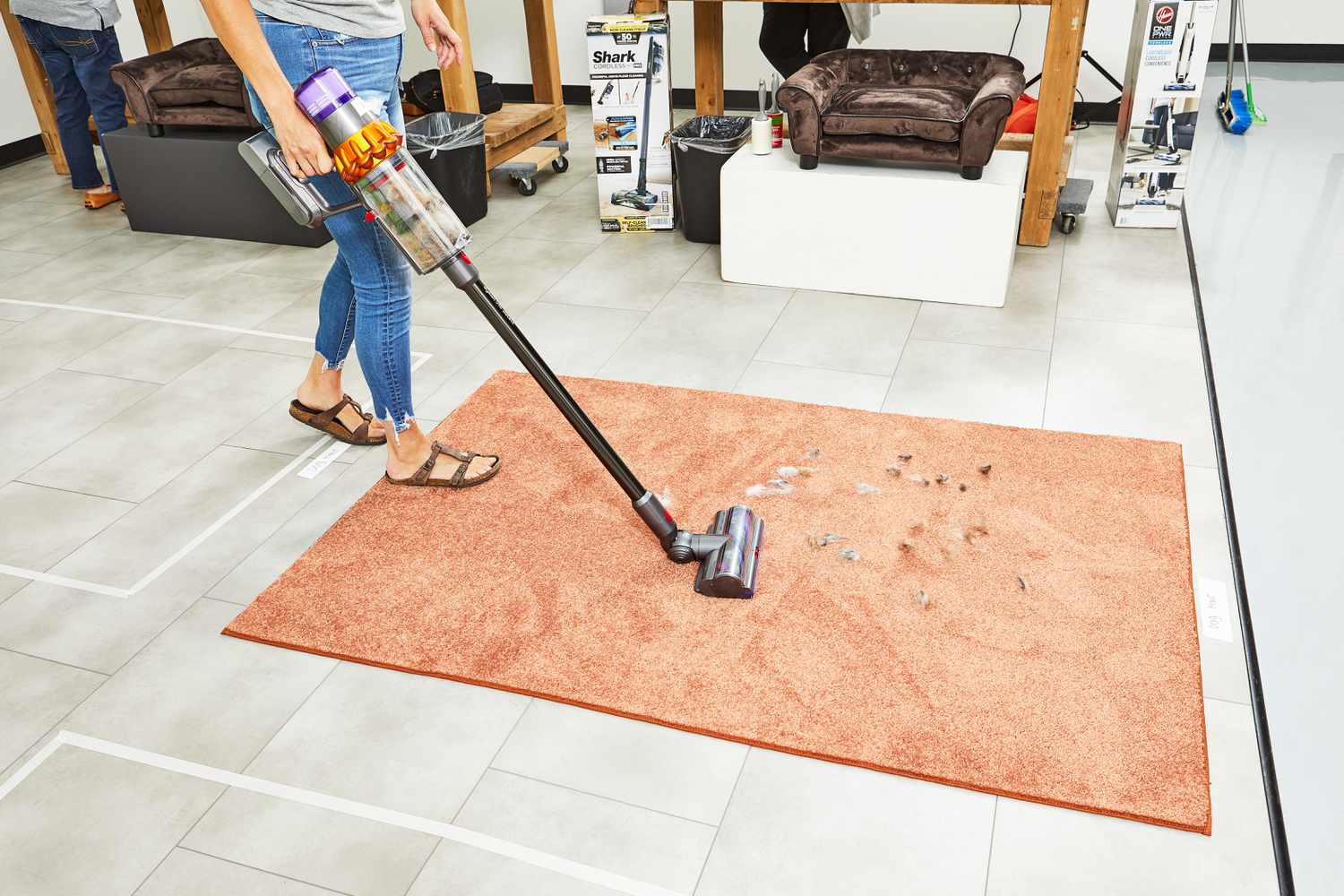 A person using a Dyson V15 Detect Cordless Vacuum Cleaner to clean fur from an orange rug