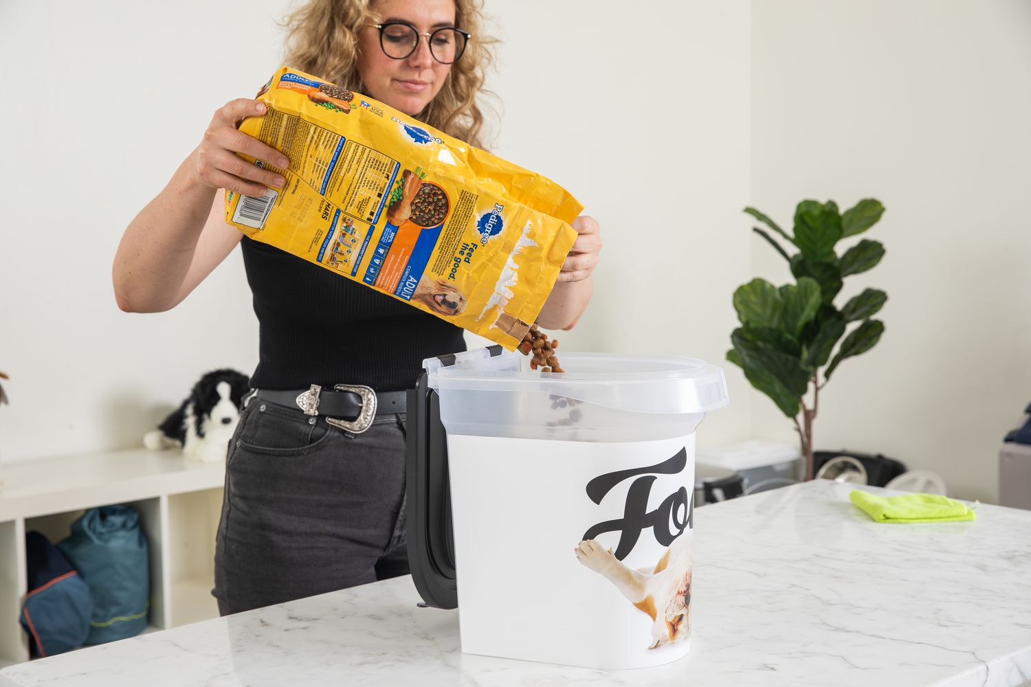 person filling Paw Prints 15 lb. Airtight Storage Container with dog food