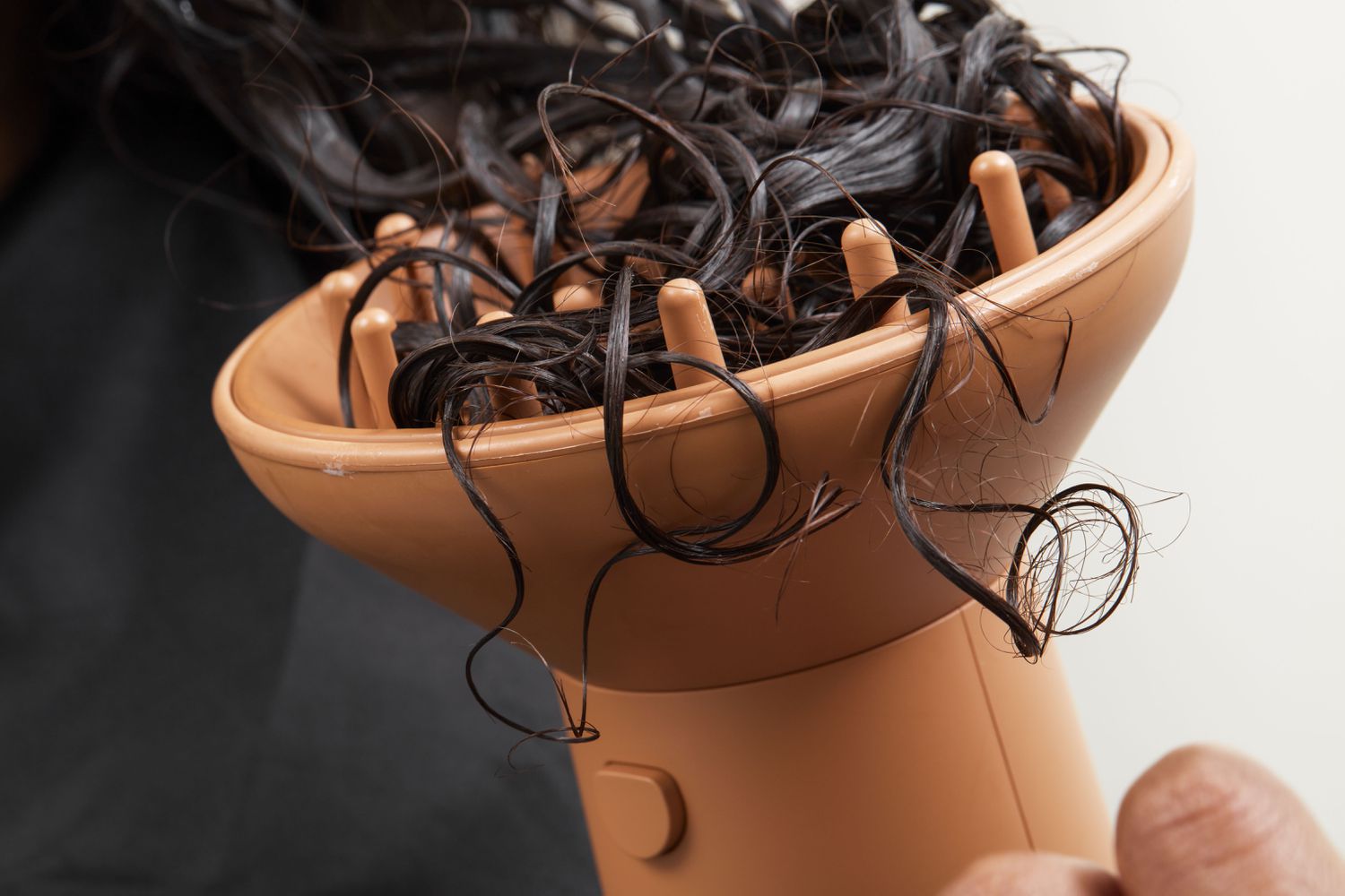 Closeup of a person using the PATTERN Blow Dryer's diffuser on curly hair.