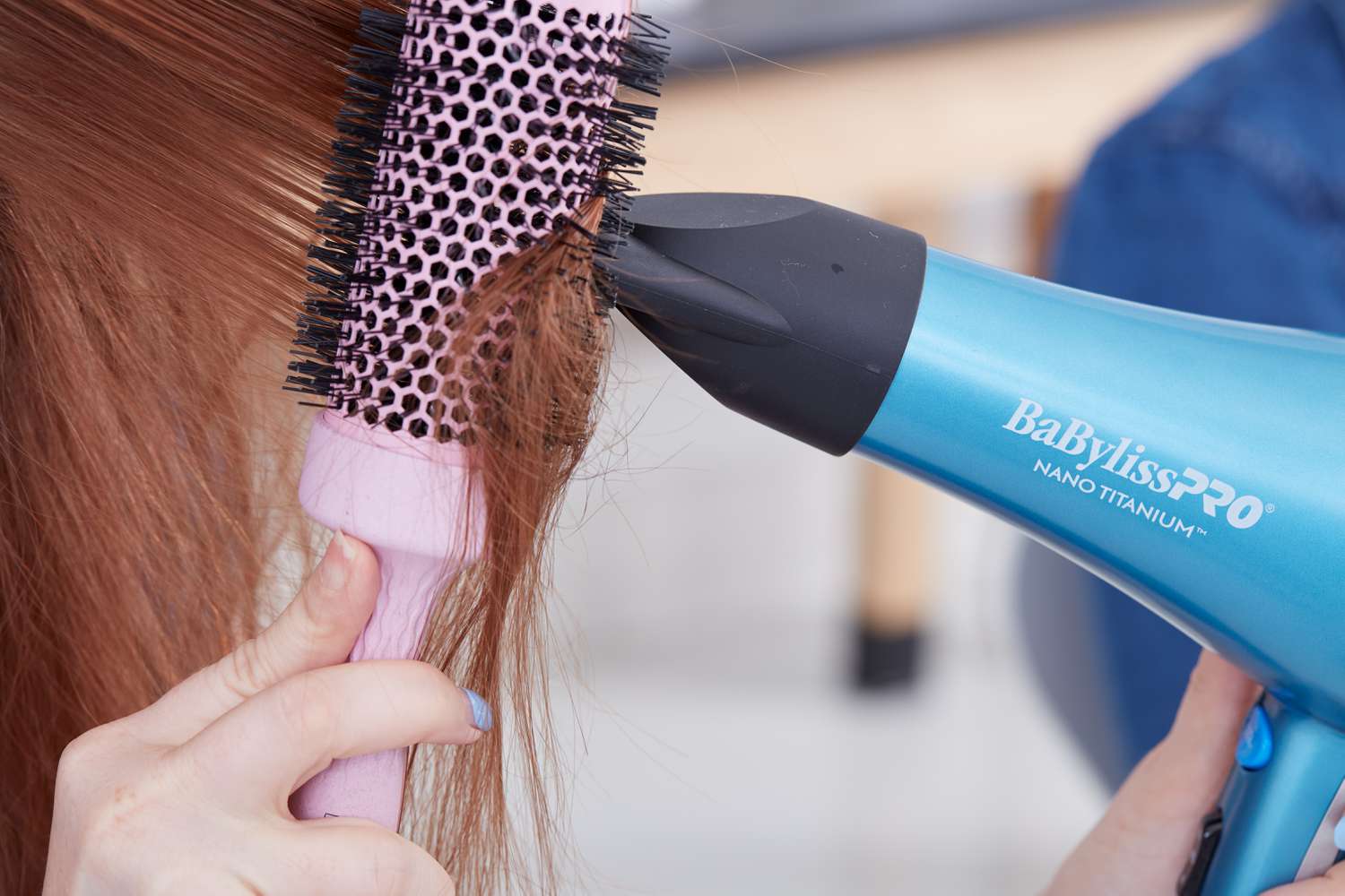 Closeup of a person using BaBylissPRO Nano Titanium Dryer and a brush to blow-dry their hair