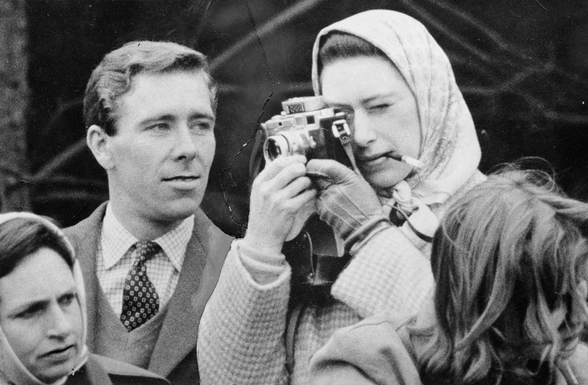 Professional photographer Antony Armstrong-Jones, the Earl of Snowdon, watches critically as his fiancee Princess Margaret (1930 - 2002) takes a snap at the Badminton Horse Trials