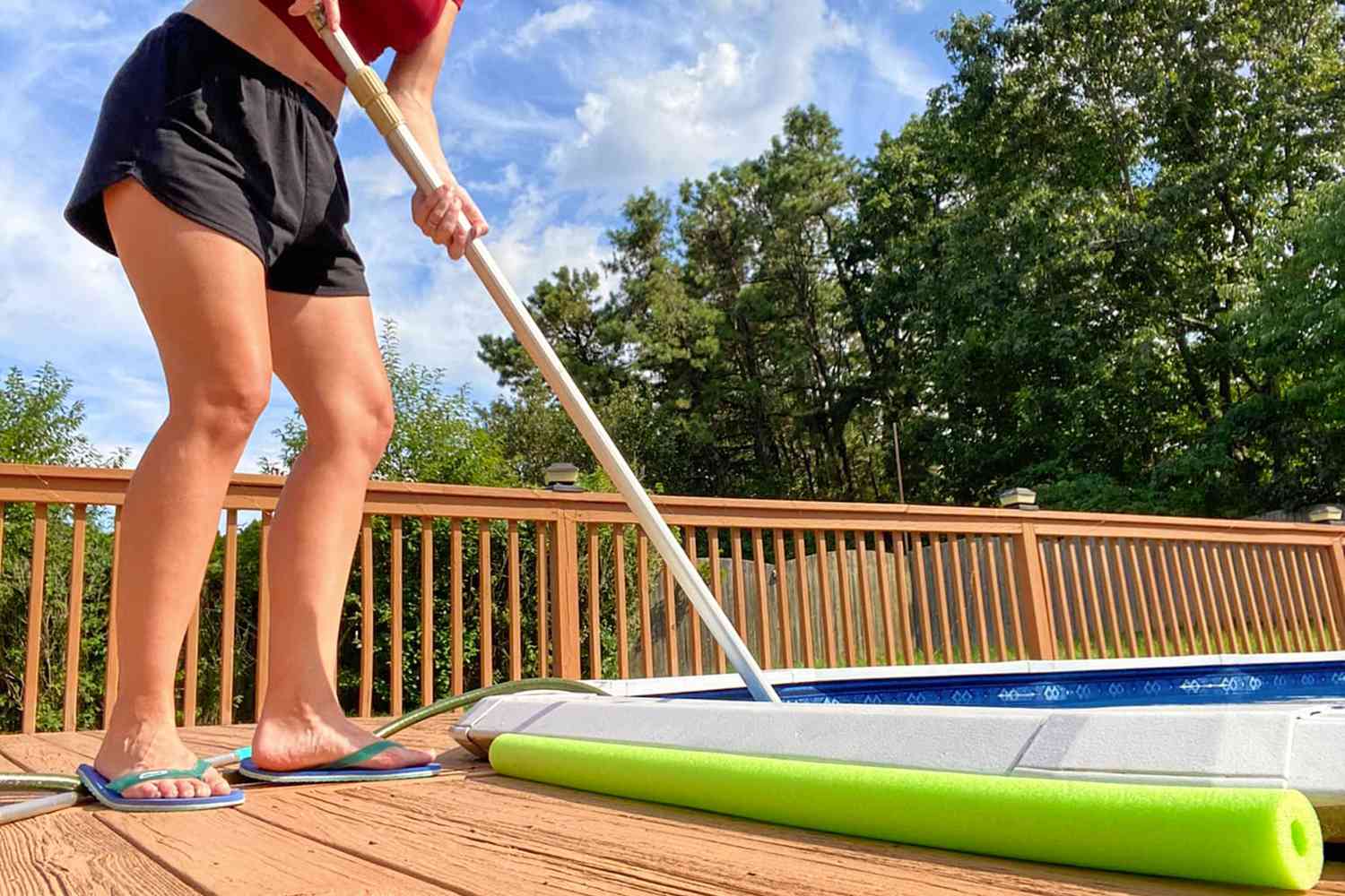 Person standing on wood deck using Poolwhale Pool & Spa Vacuum