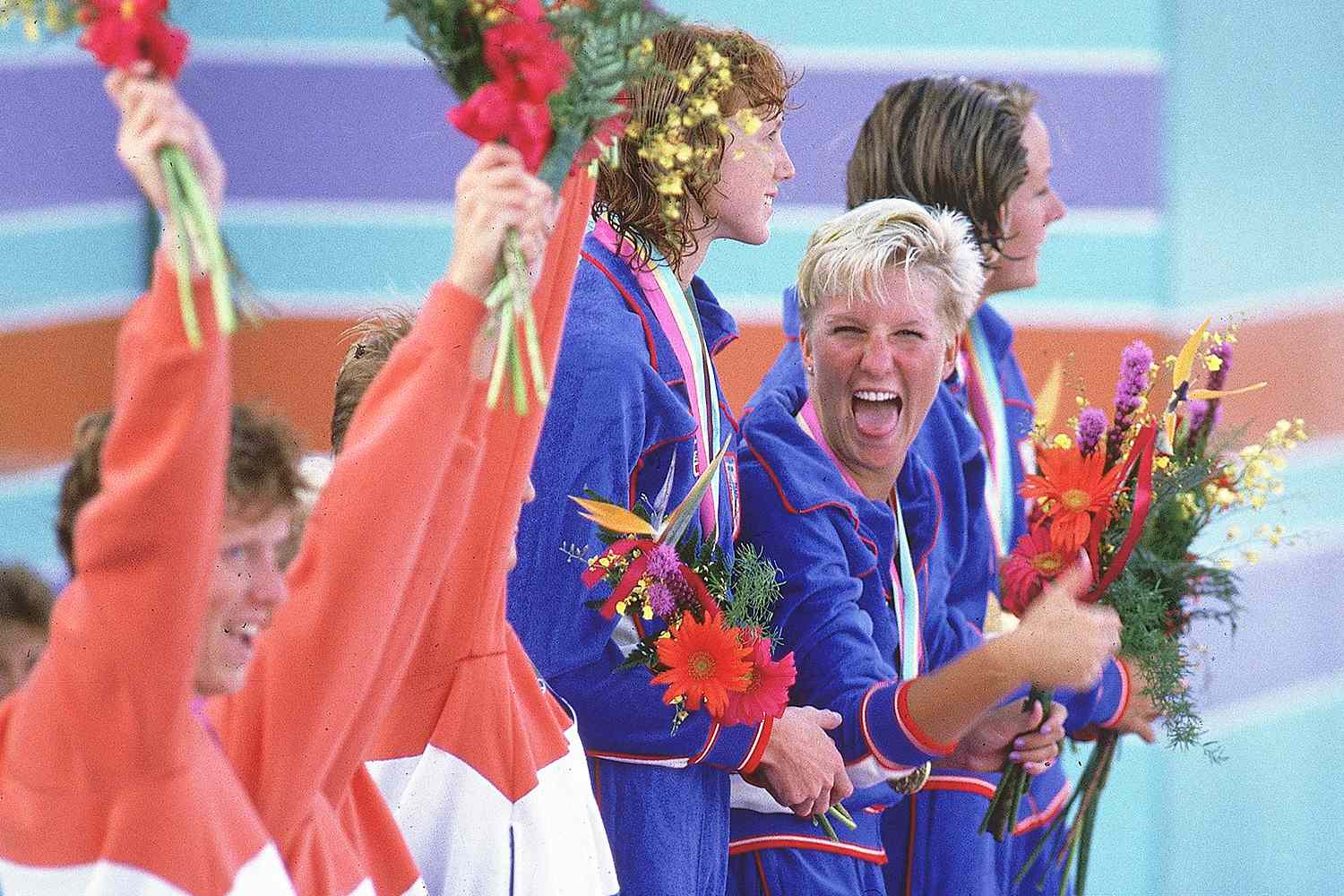 Carrie Steinseifer victorious with gold medal and team on stand during awards ceremony after winning 4X100M freestyle competition in 1984.