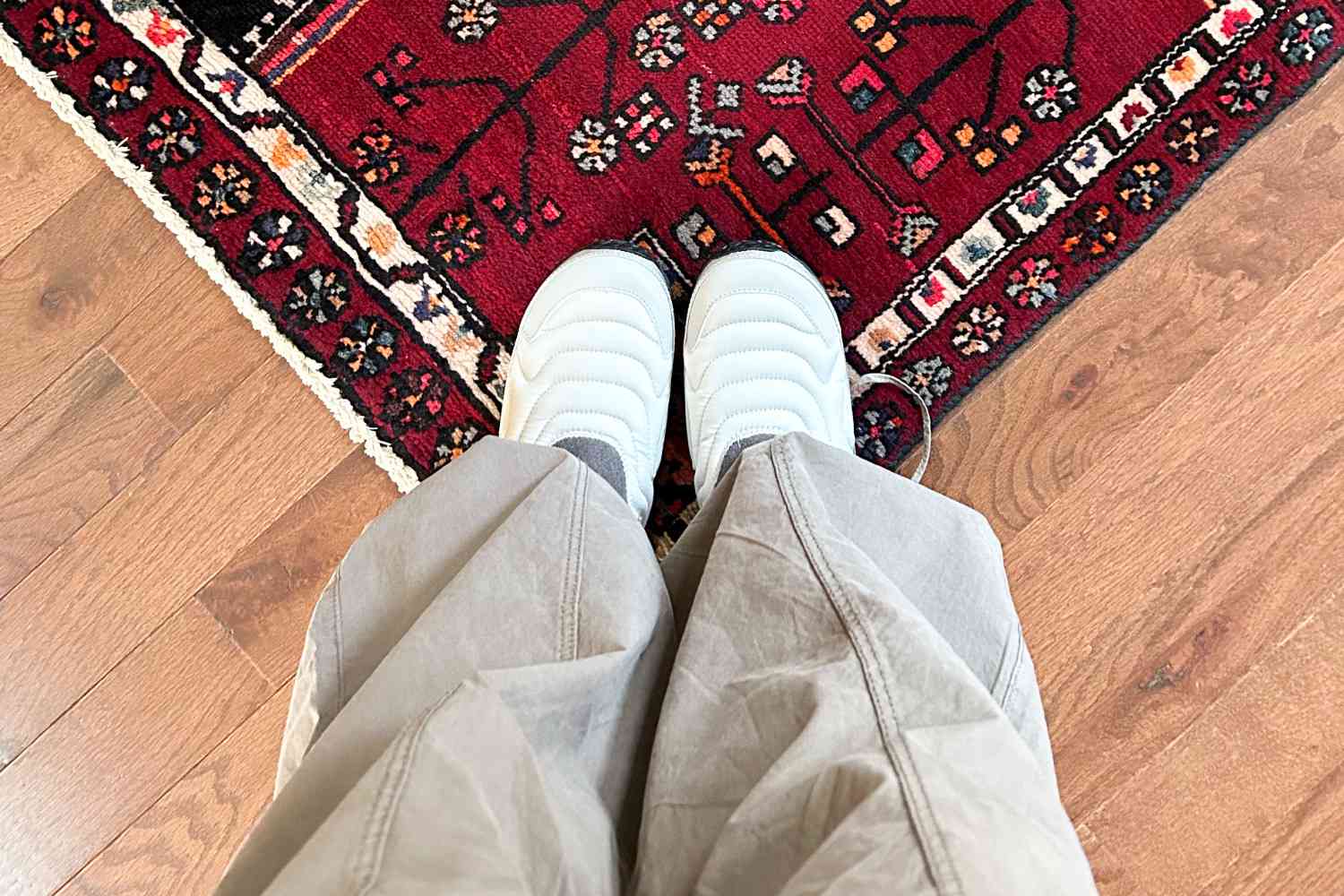 A person wearing the ReEmber Terrain and standing on a colorful rug