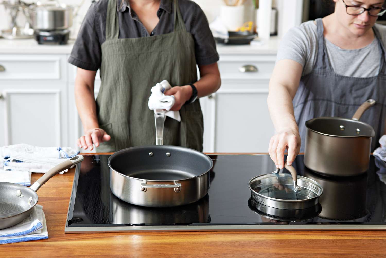 two people looking at non-stick pots and pans on a stovetop