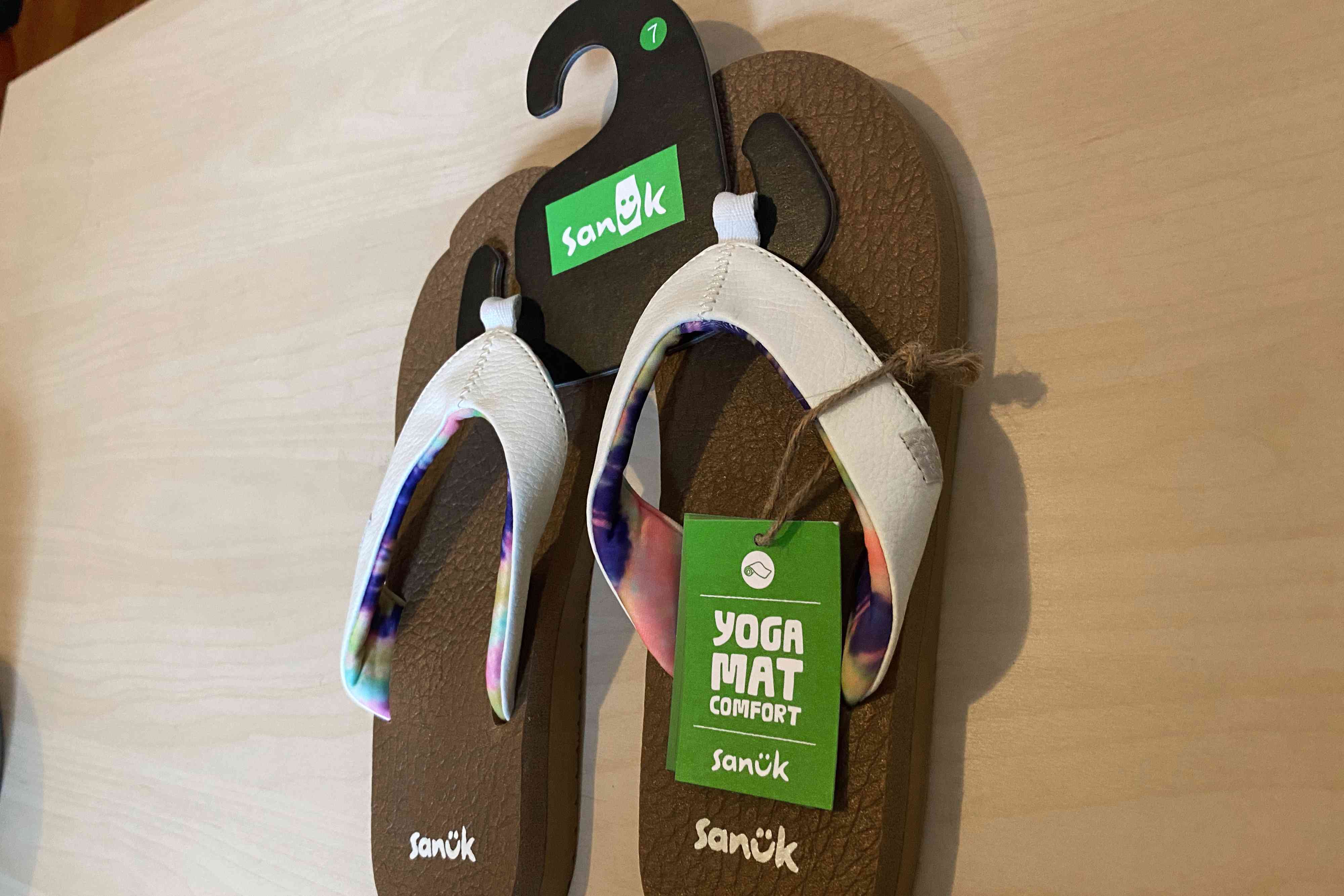 Sanuk Yoga Mat Flip Flops with tags on a wooden surface 