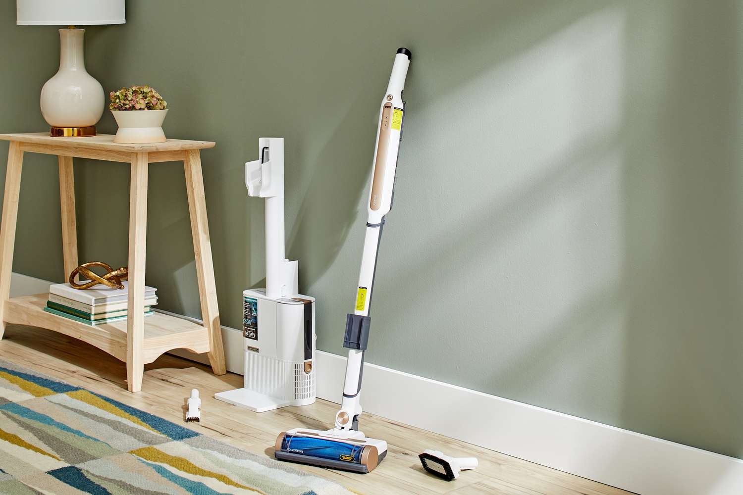 Shark WS642AE Wandvac Cordless Stick Vacuum with Self-Empty Charging is leaned on wall next to a wooden table