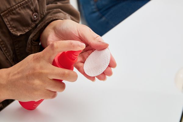 Person spraying Tower 28 SOS Daily Rescue Facial Spray on a cotton round 