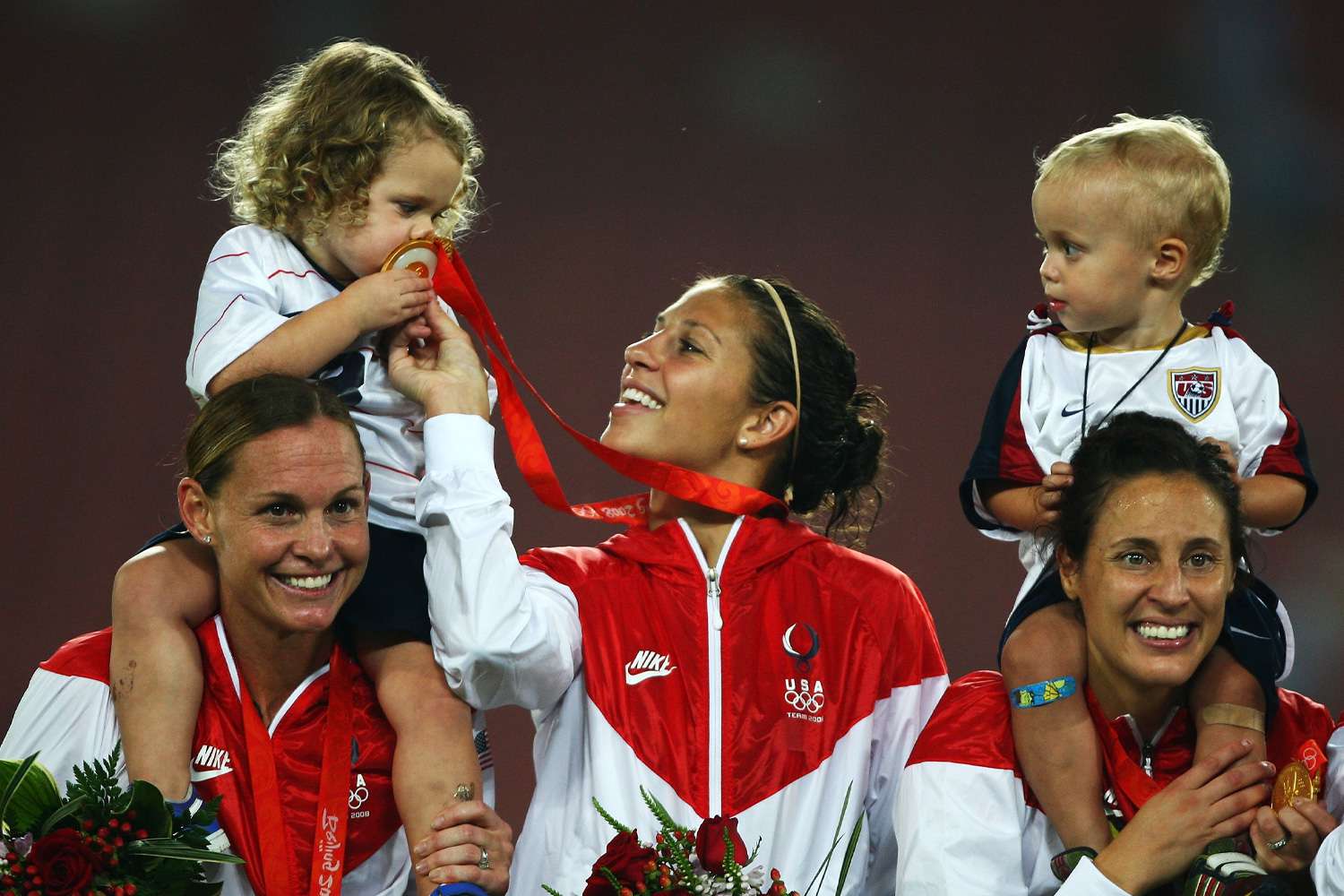 USA team members Christie Rampone, Carli Lloyd, Kate Markgraf and children pose on the podium with their Gold medals after the Women's Football on Day 13 of the Beijing 2008 Olympic Games on August 21, 2008
