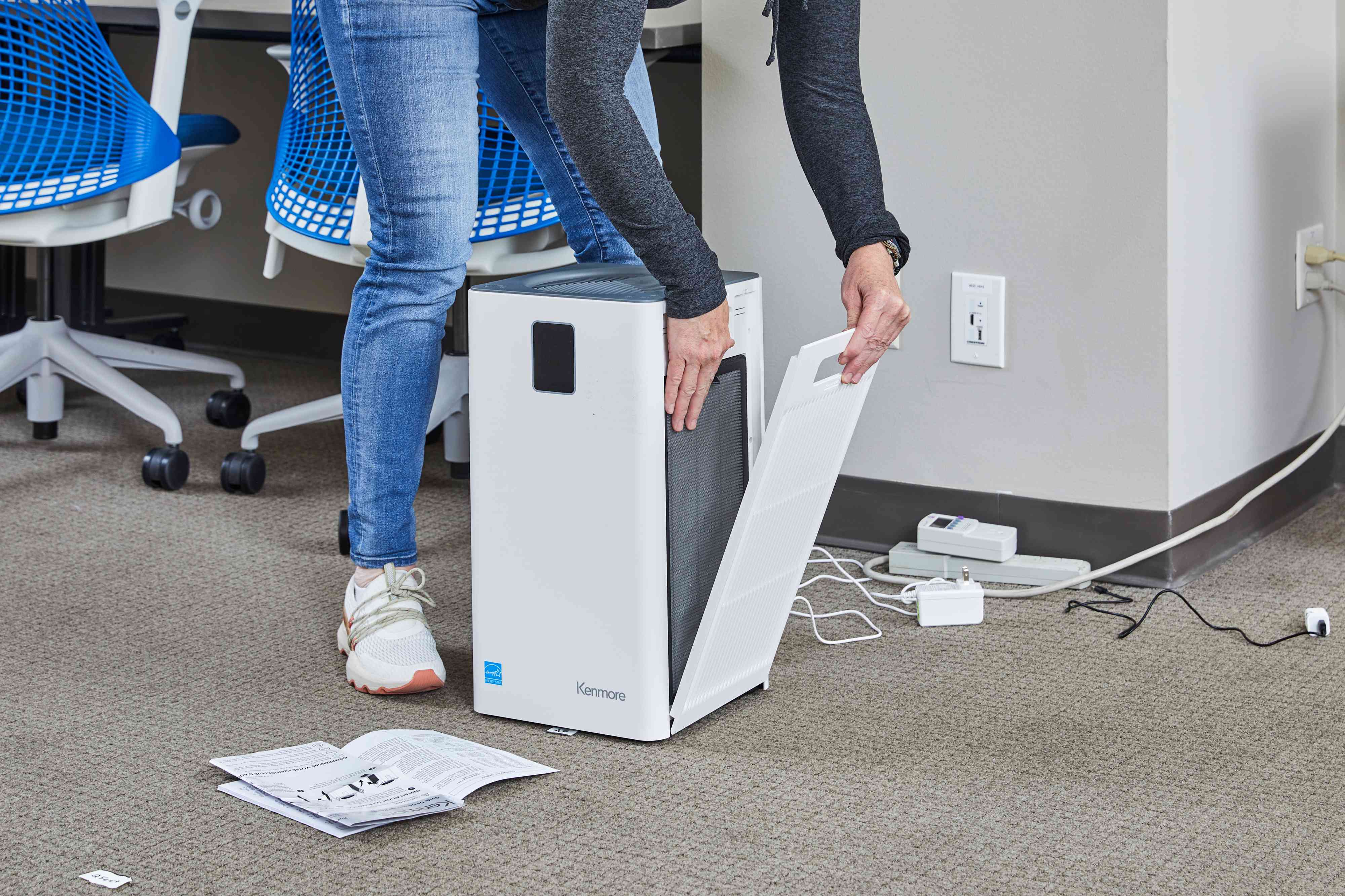 A person opens up the side panel to the Kenmore 1500e Air Purifier's filter.