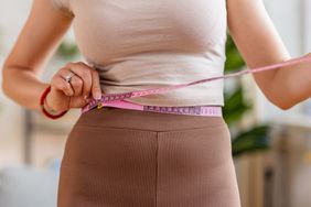 young woman measuring her waist with a measuring tape