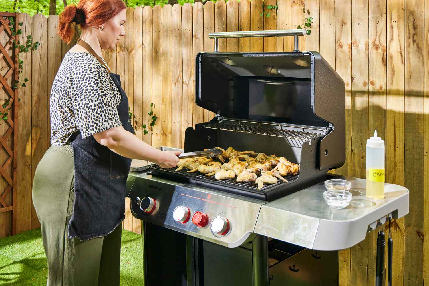 A person turns chicken cooking in the Weber Genesis E-325 Liquid Propane Gas Grill