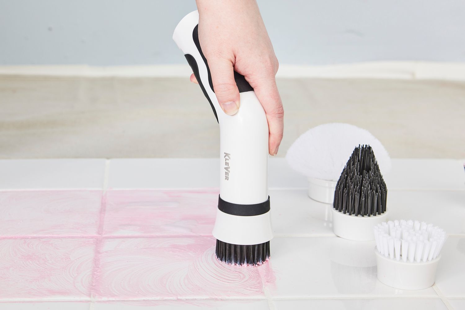 Person cleans white tile stained with red marker with a Klever Electric Spin Scrubber with 8 Brushes