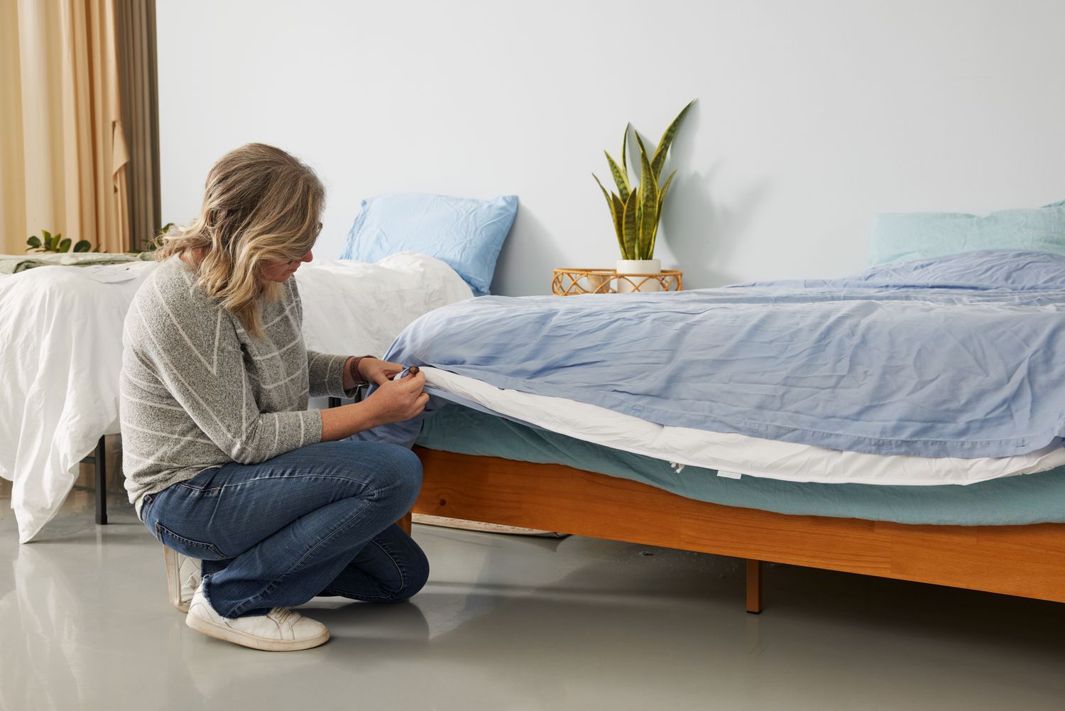 A person fixing a bed with the Sijo AiryWeight Eucalyptus Duvet Cover on top