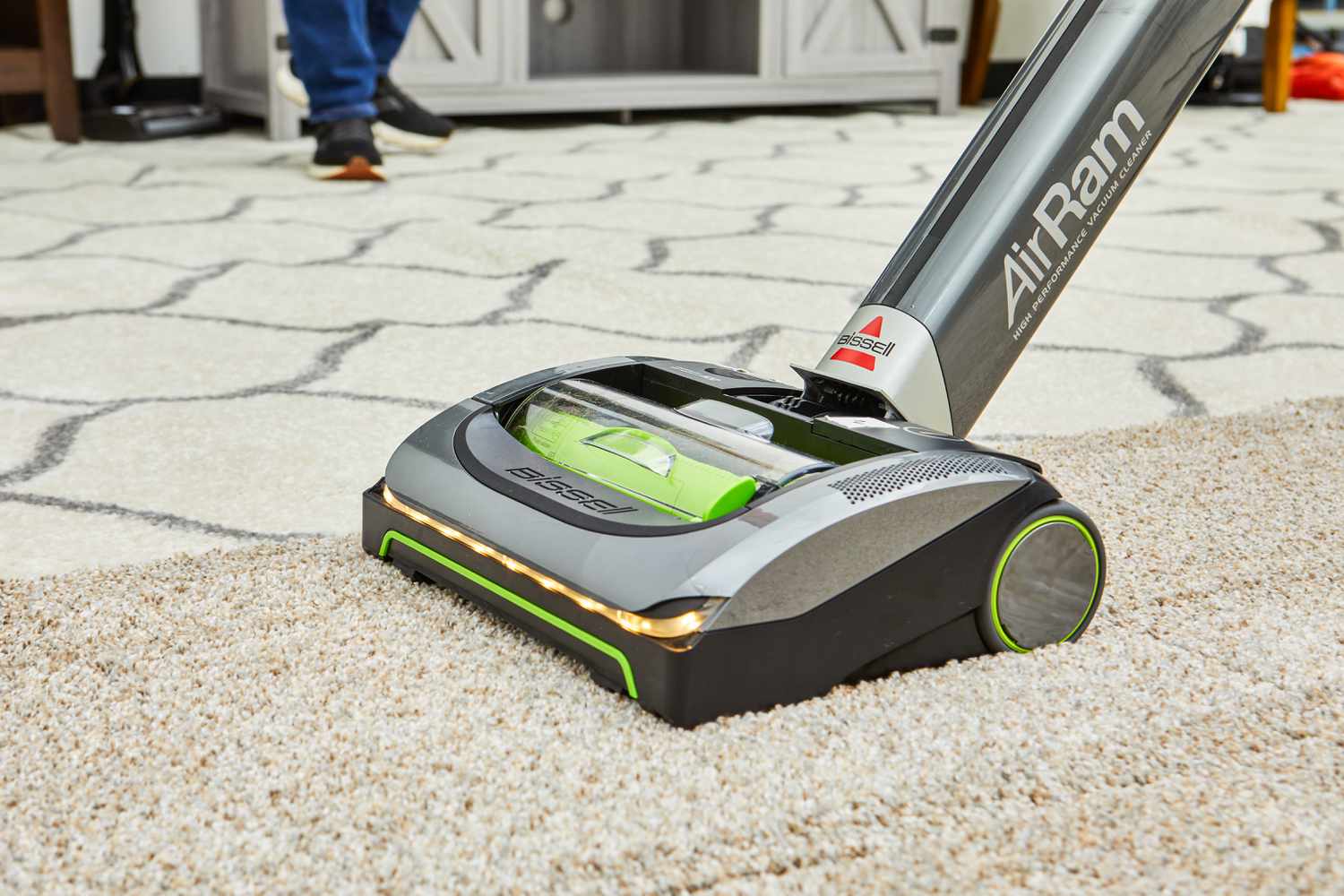 A person vacuums a high pile rug using the Bissell 1984 Air Ram Cordless Vacuum.