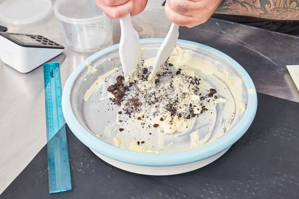 Closeup of hands using utensils to mix crushed cookies into the ice cream in the Chef'n Sweet Spot Ice Cream Maker