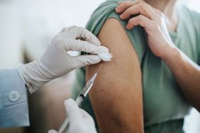 Close up of senior Asian woman getting Covid-19 vaccine in arm for Coronavirus immunization by a doctor at hospital. Elderly healthcare and illness prevention concept