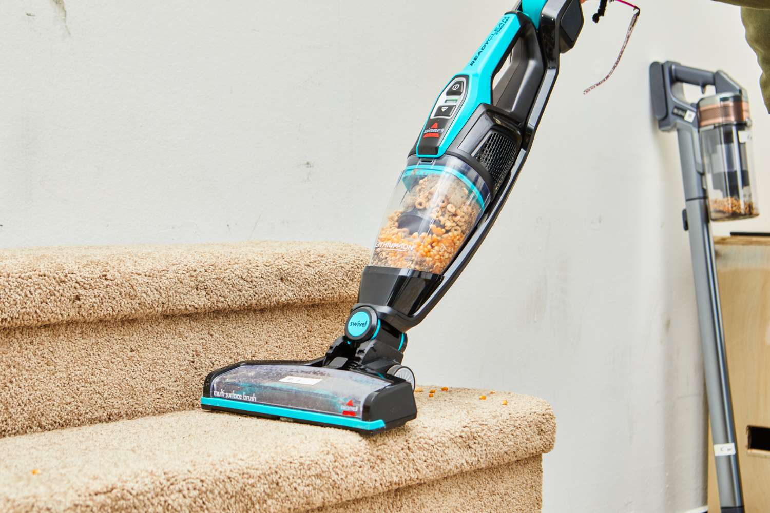 A person using the BISSELL 3061 Featherweight Cordless Stick Vacuum on stairs with carpet.