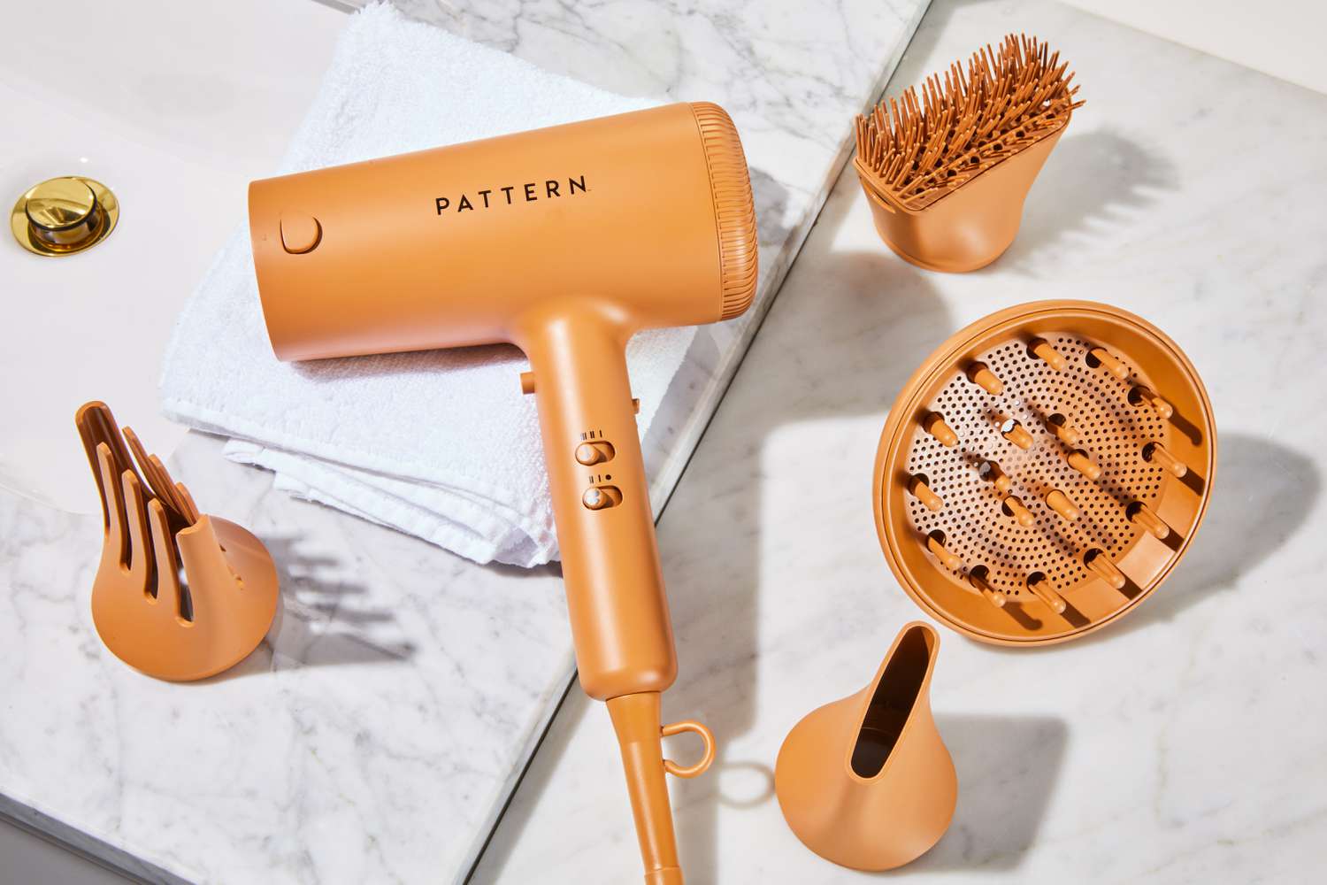 The PATTERN Blow Dryer and accessories on a white counter.