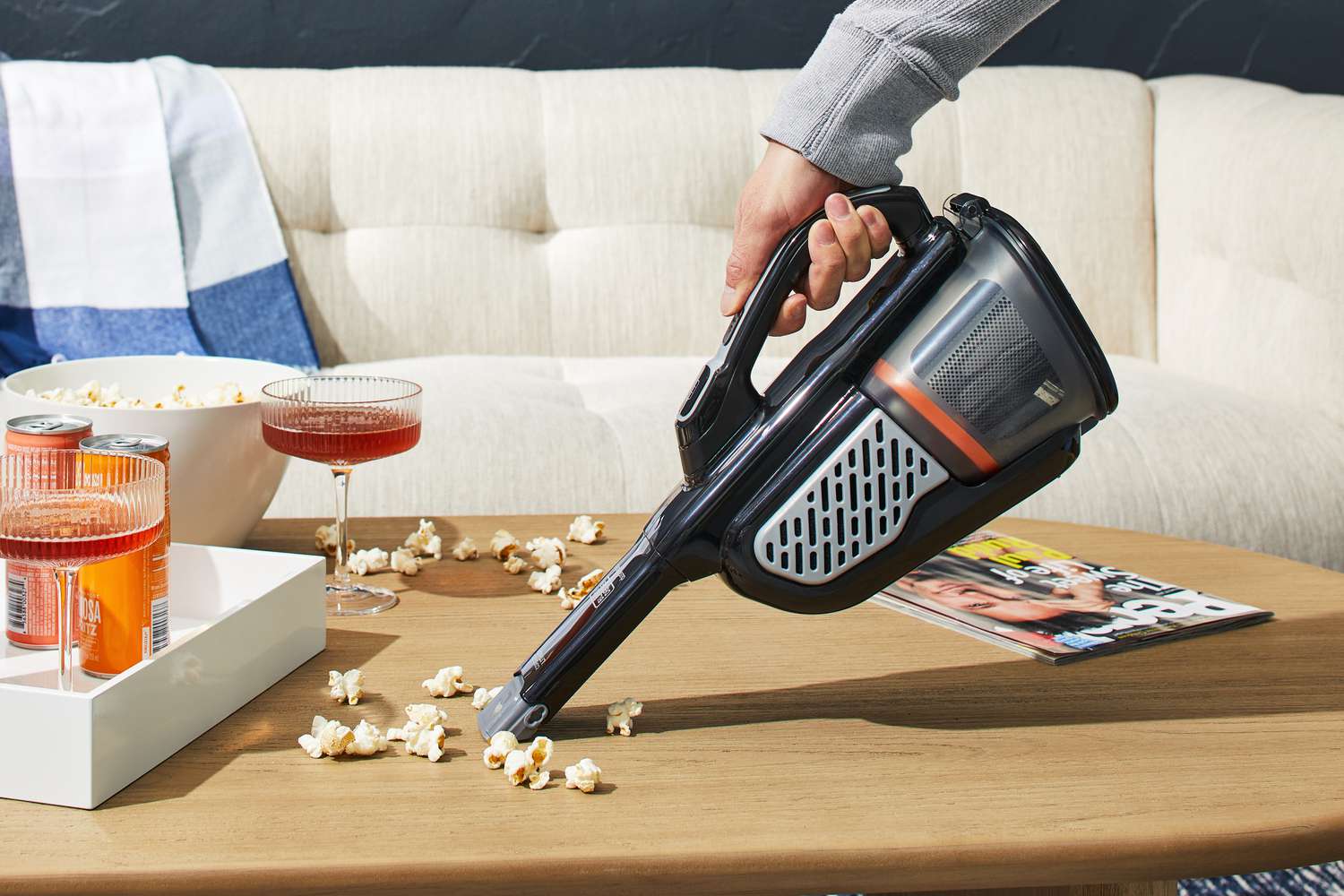 Person using Black+Decker Dustbuster AdvancedClean+ Cordless Hand Vacuum to clean popcorn from coffee table