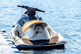 Jet ski tied by a rope to a modular floating plastic pontoon berth at seaside resort