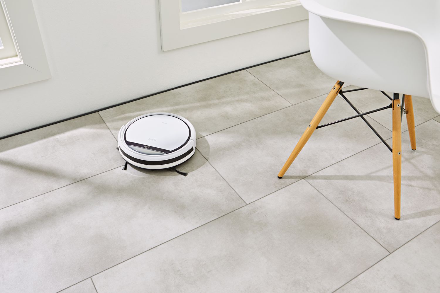ILIFE V3s Pro Robot Vacuum Cleaner cleaning tile next to chair