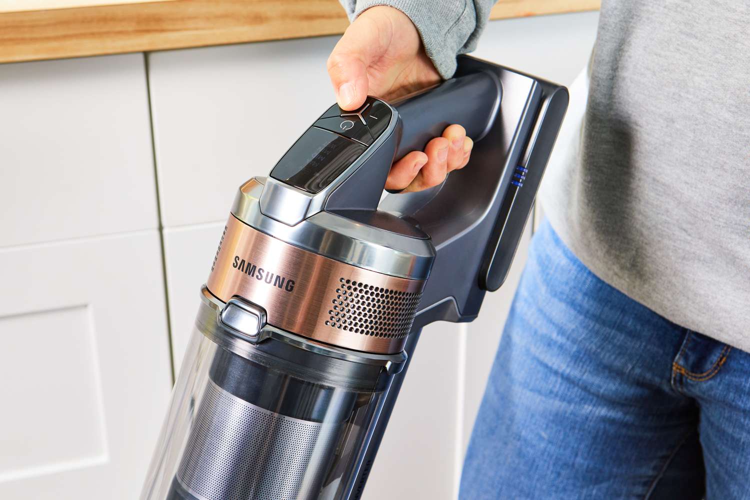 Person pressing a power button of the Samsung Jet 75 Cordless Stick Vacuum