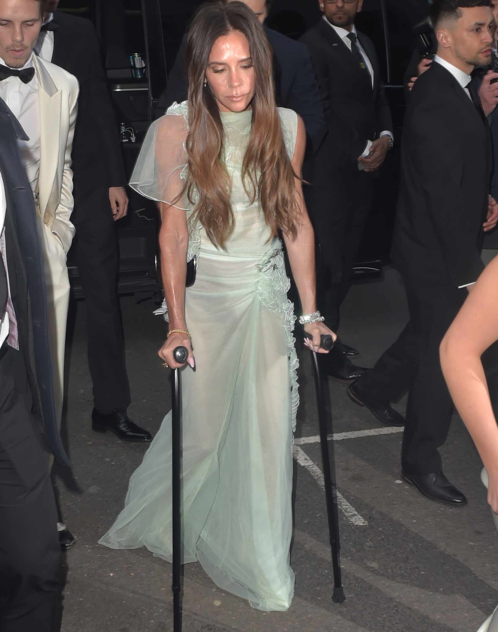 Style icon Victoria Beckham gracefully arrives At Her 50th Birthday Party , adding her signature elegance even with a crutch in hand.