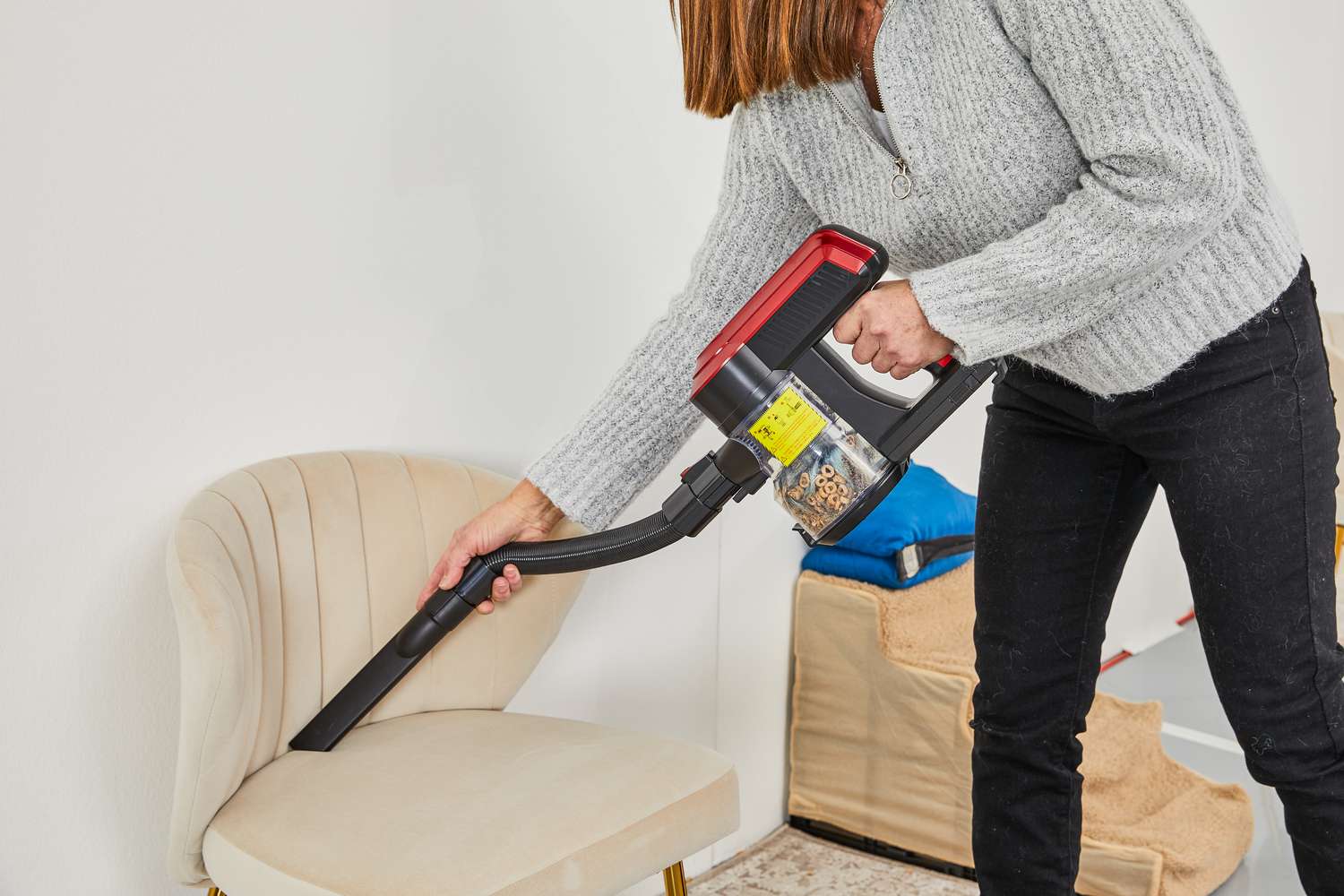 Person using the Moosoo K23 Pro Cordless Stick Vacuum to clean a beige chair 