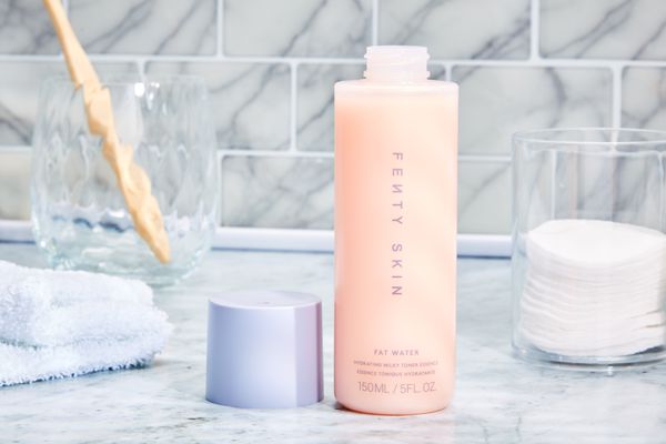 Fenty Beauty Fat Water Hydrating Milky Toner Essence with Hyaluronic Acid and Tamarind on a marble bathroom counter 