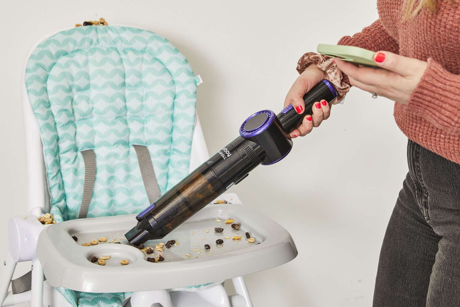 Person using Nicebay Handheld Cordless Vacuum to clean food from highchair