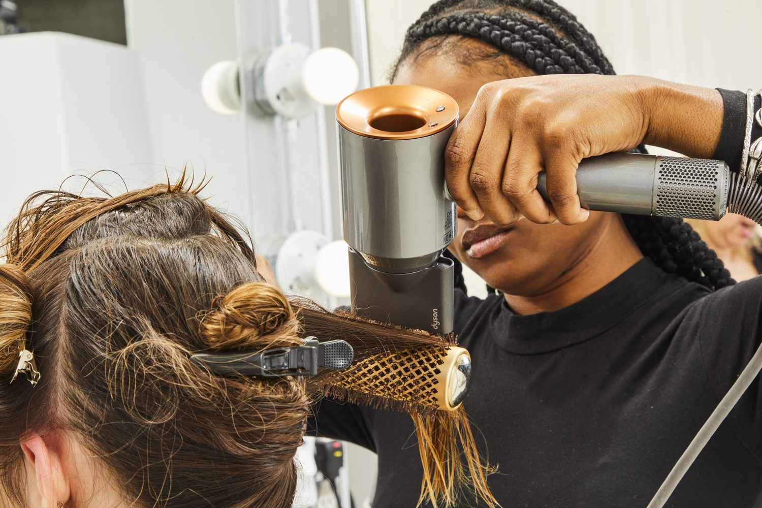 Woman using a Dyson Supersonic Hair Dryer on another persons hair with a brush