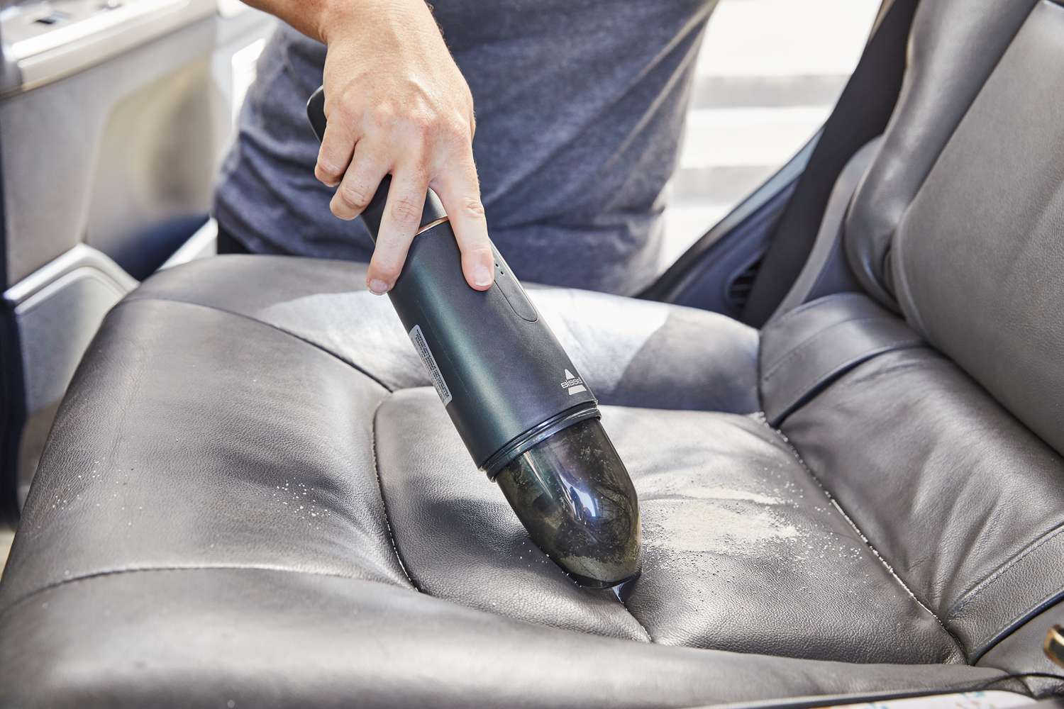 person cleans car seat with BISSELL AeroSlim Lithium Ion Cordless Handheld Vacuum