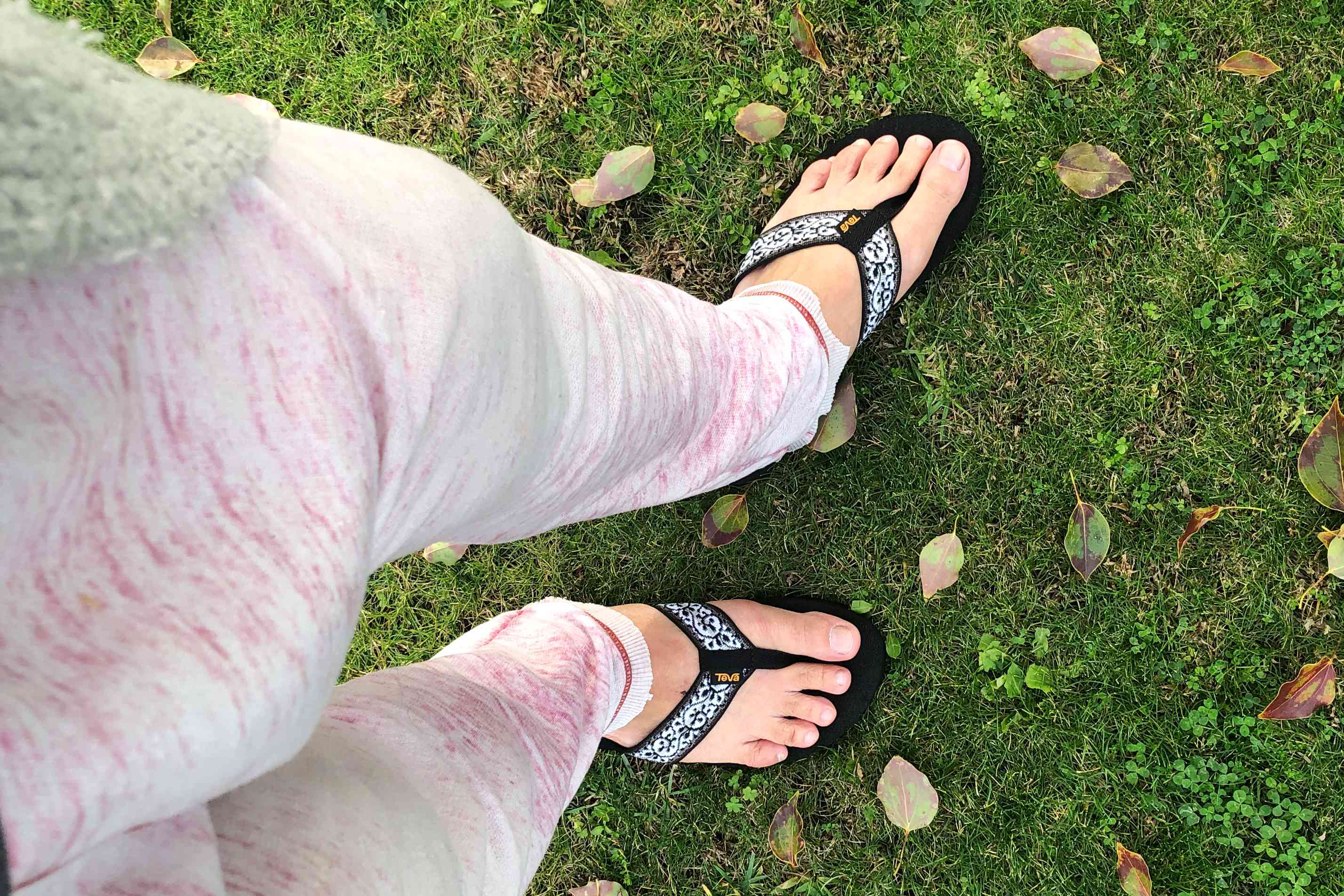Feet wearing the Teva Womens Mush II Flip Flops on grass 