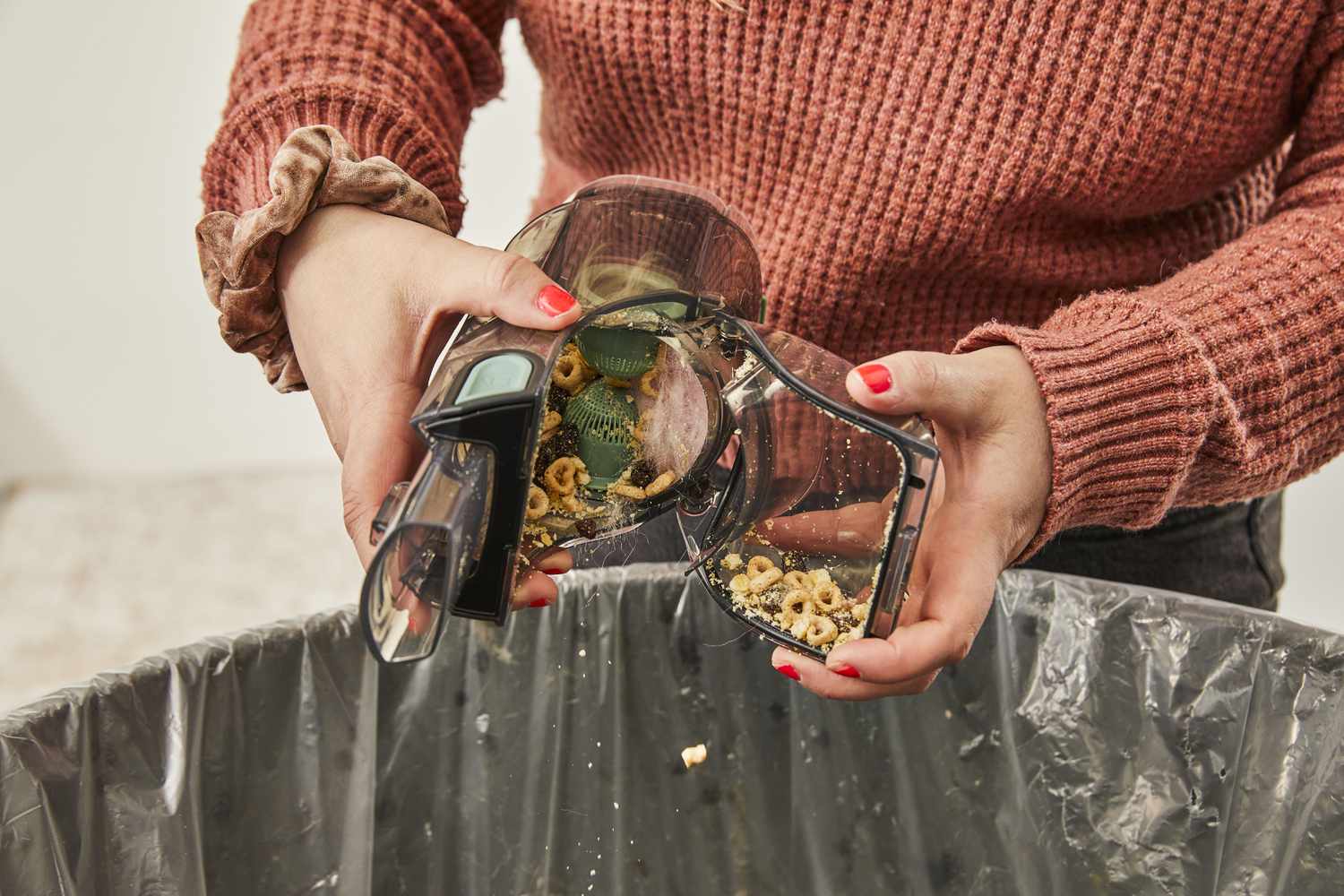 Person emptying the Shark UltraCyclone Pro Cordless Handheld Vacuum into trash can