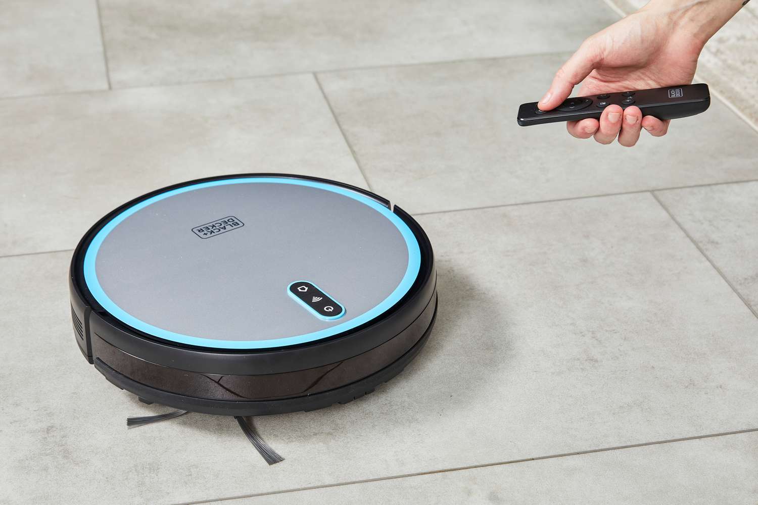 A person uses the remote to control the Black + Decker RoboSeries Robot Vacuum 
