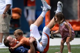 Peyton Manning (18) has a little fun with his son Marshall who tackles him and his daughter Mosley (R) after practice on day four of the Denver Broncos 2014 training camp July 27, 2014 at Sports Authority Field at Mile High