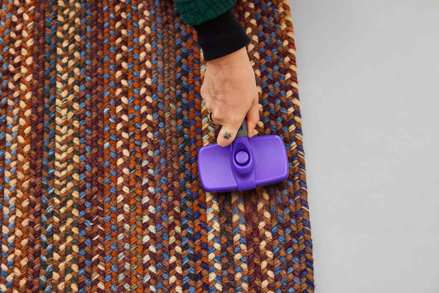 A person brushes the L.L.Bean Braided Wool Rug, Oval