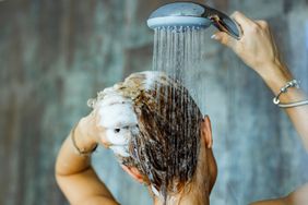 Back view of a woman washing her hair with a shampoo in bathroom