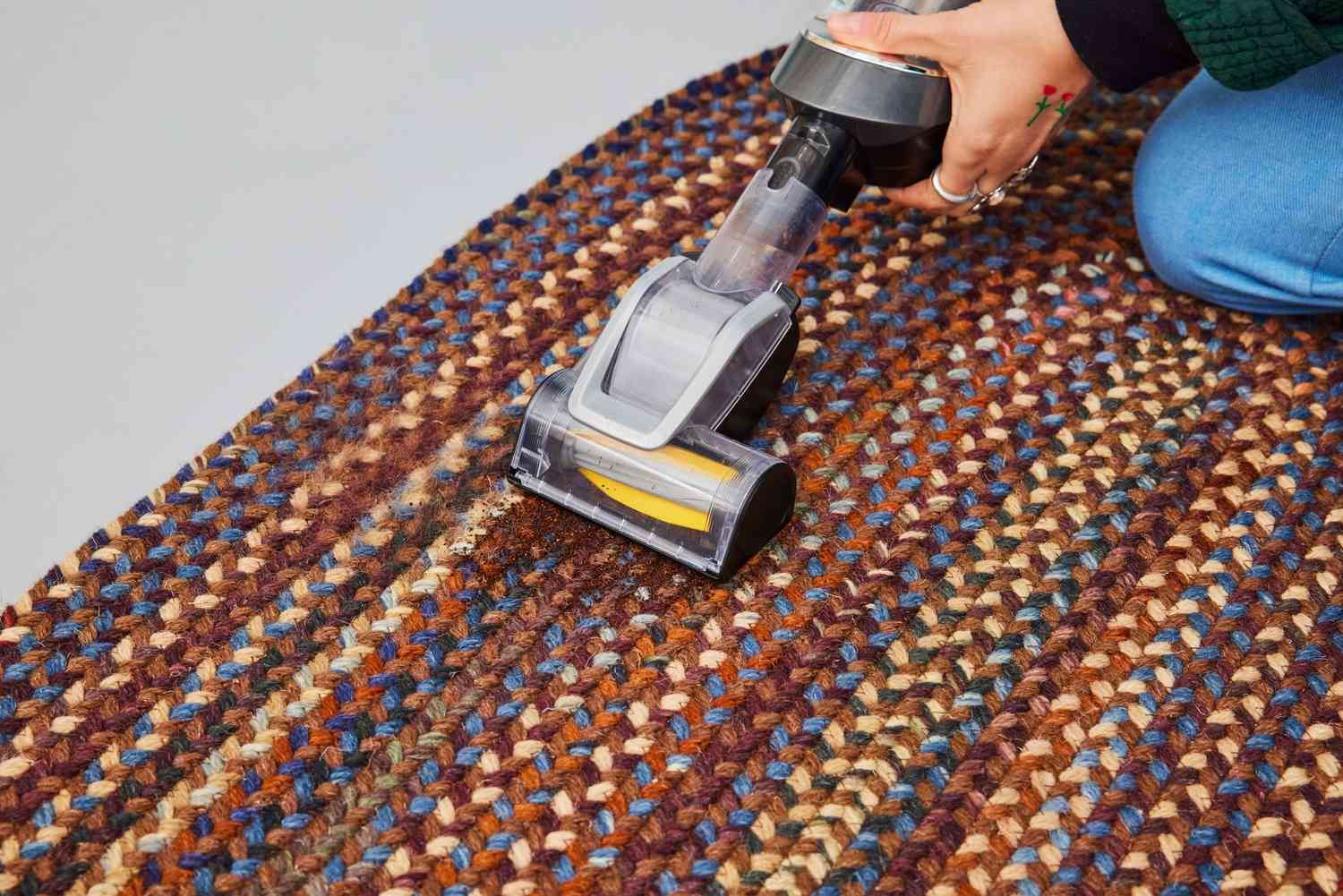 A person vacuums the L.L.Bean Braided Wool Rug, Oval