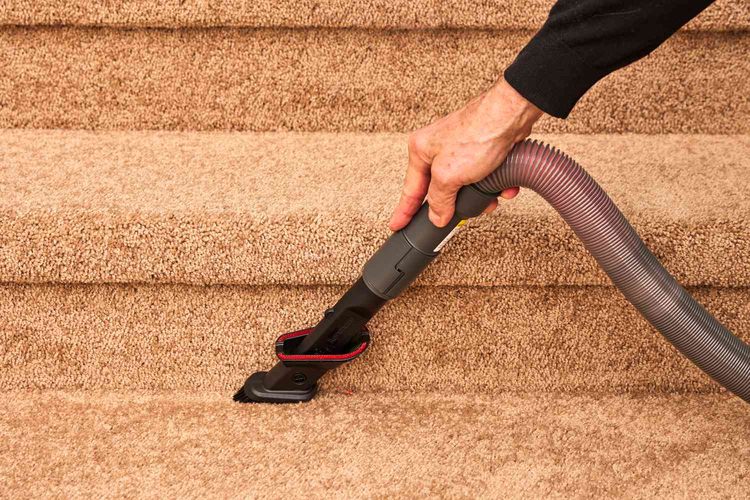 A person uses the brush attachment on the Kenmore Allergen Seal Bagless Upright Vacuum