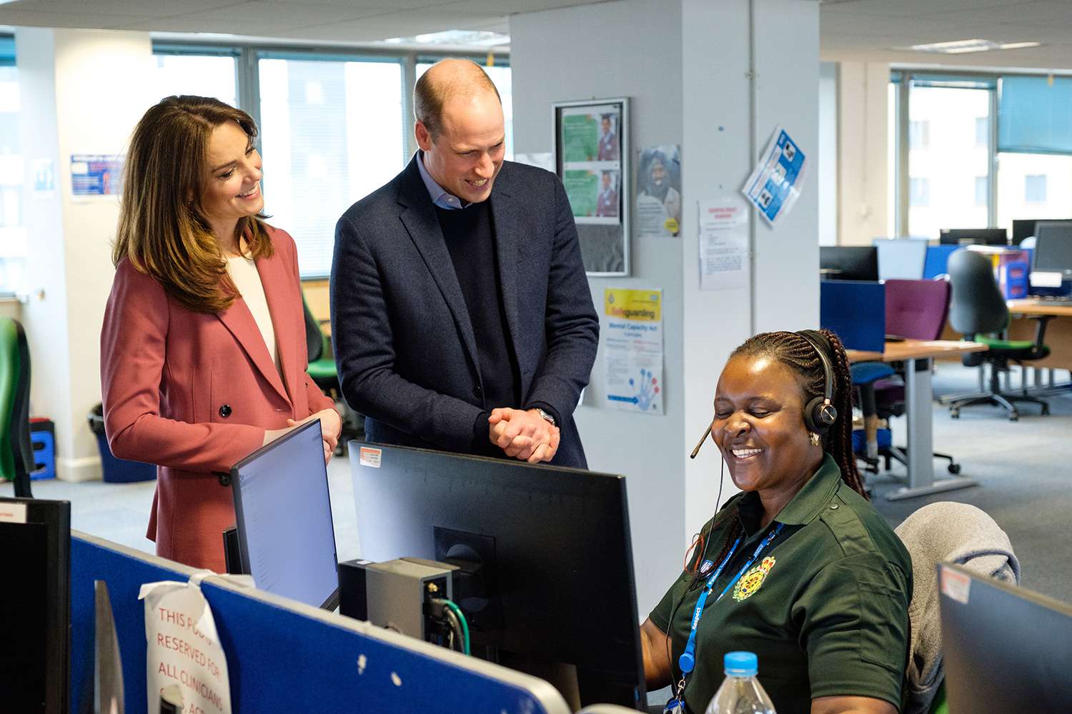 Palace of the Duke and Duchess of Cambridge talking with Chief Executive of the London Ambulance Service, Garrett Emmerson, and an unidentified staff member (left) during a visit to the London Ambulance Service 111 control room in Croydon on Thursday to meet ambulance staff and 111 call handlers who have been taking NHS 111 calls from the public, and thank them for the vital work they are doing.