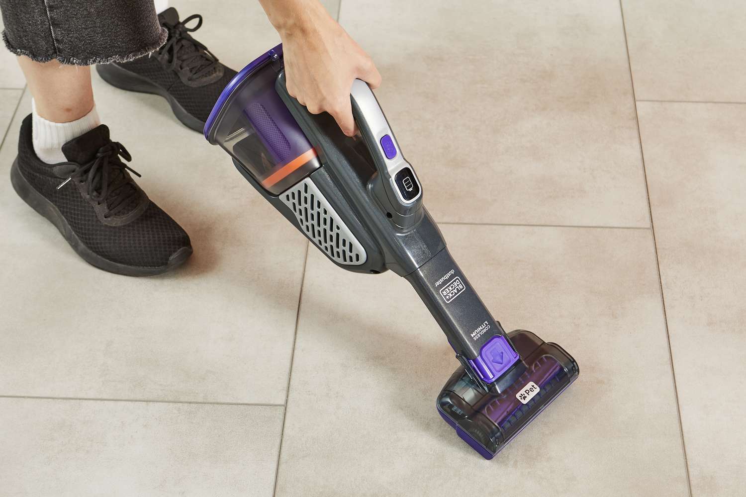 Hand using the Black+Decker Dustbuster AdvancedClean+ Pet Cordless Hand Vacuum Cleaner to clean tile floor