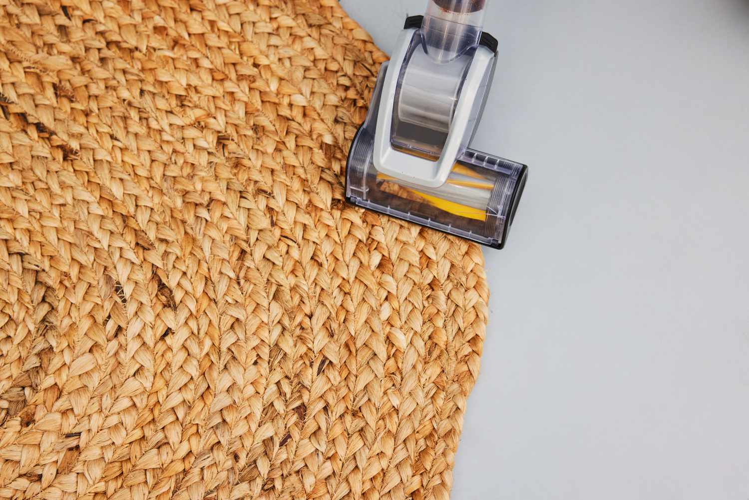 A person vacuums the nuLOOM Rigo Hand Woven Jute Area Rug