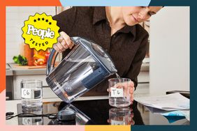 person pours water from water filter pitcher into glass in kitchen