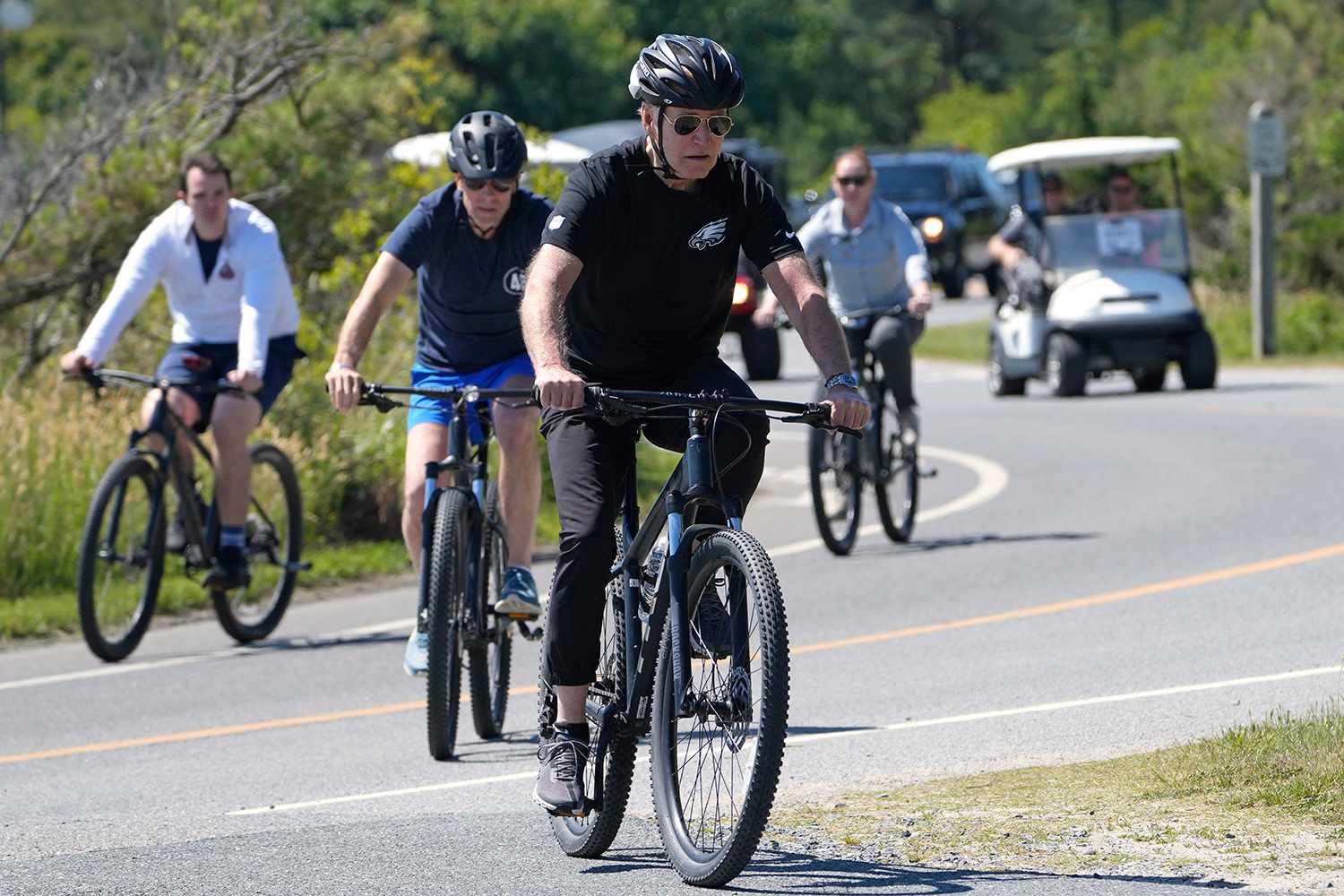 President Joe Biden, center, followed by his son Hunter Biden, bike at Gordons Pond State Park