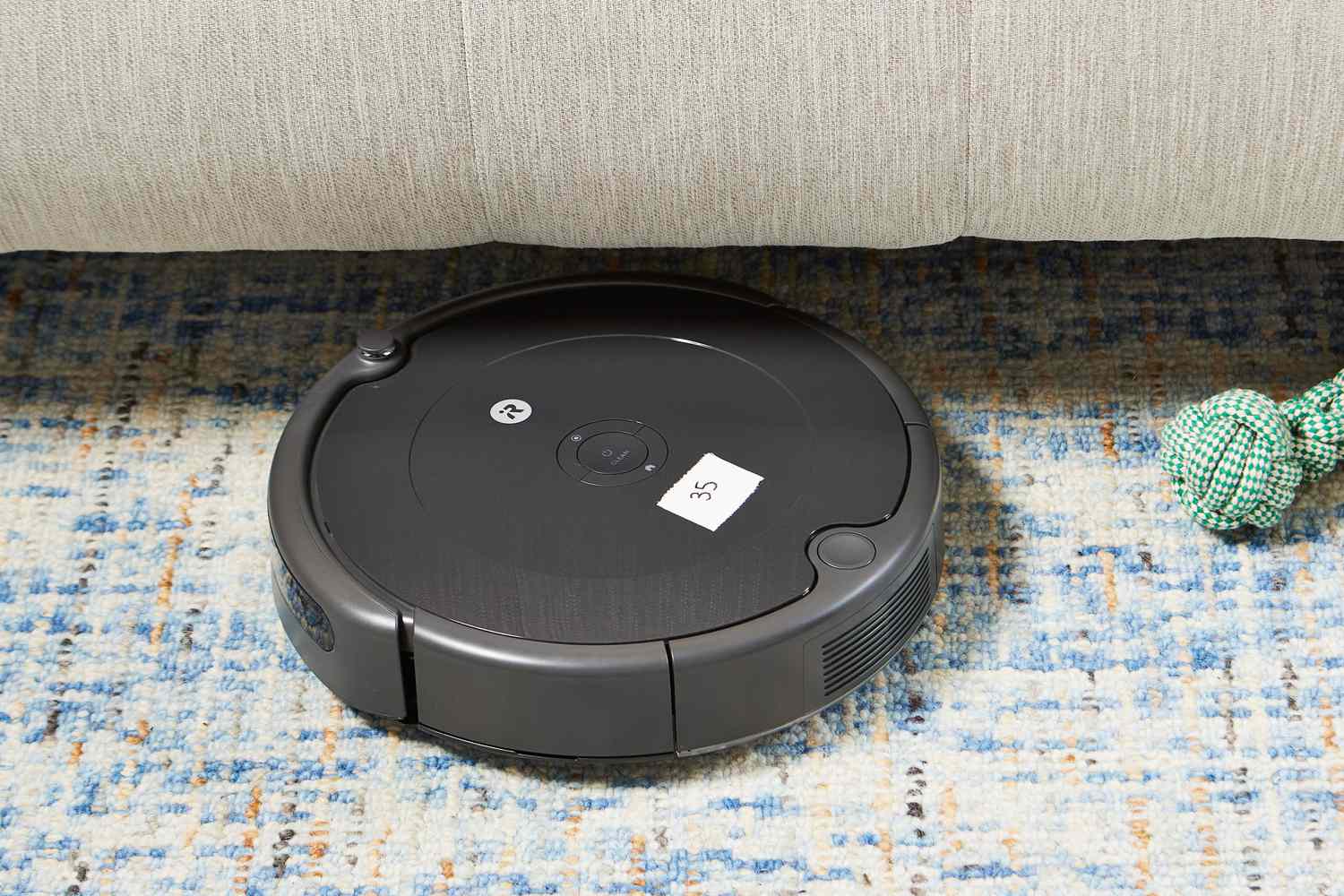 iRobot Roomba 694 Robot Vacuum on a rug going under couch with dog toy on floor