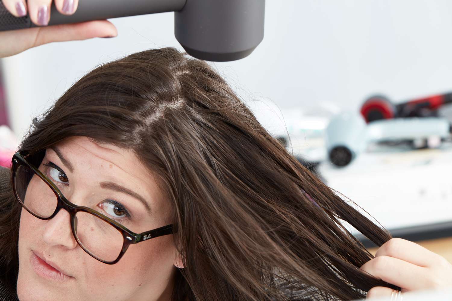 Woman using a Dyson Supersonic Hair Dryer on the top section of her hair